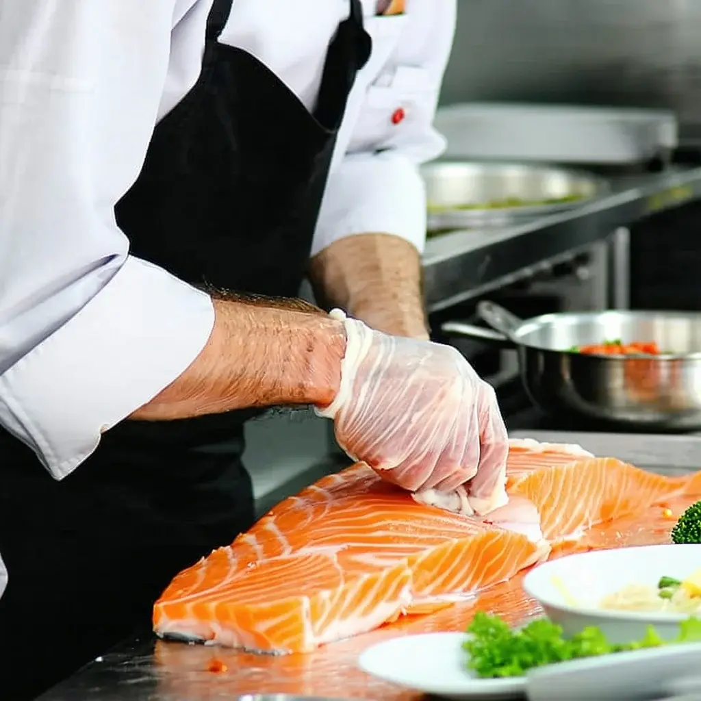 A seafood restaurant chef preparing fresh fish on a workbench before cooking
